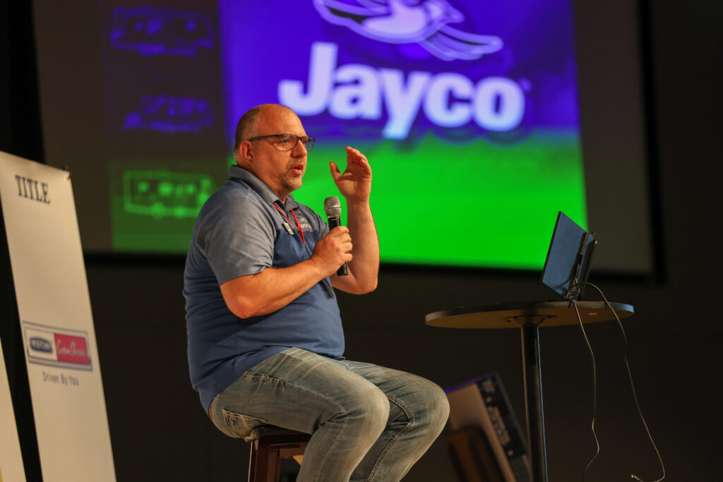 Speaker on stage in front of the Jayco screen